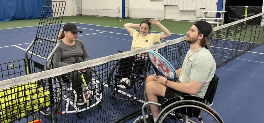 Logan Cover (center) chats with fellow adaptive athletes at a UC wheelchair tennis practice.