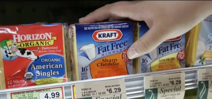 A hand reaches for a package of KRAFT fat free cheese.