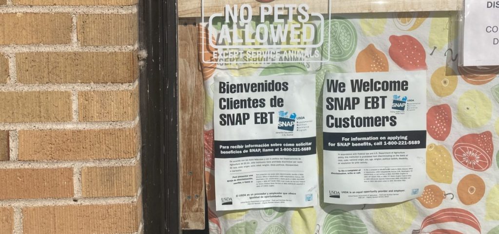 Notices posted on a storefront window in English and Spanish indicate that the store accepts EBT.