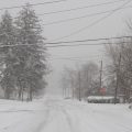 A residential street covered with snow during a snowstorm.