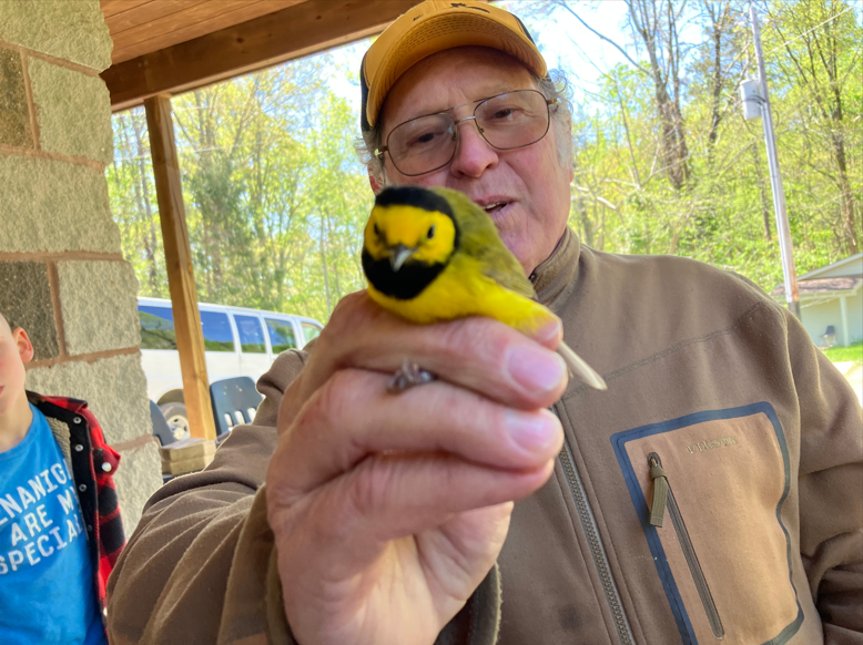 A man holds a bird close to the camera.