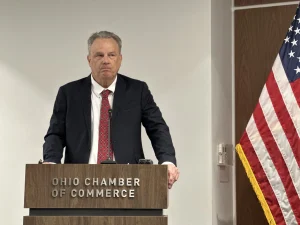 Tony Long stands with his hands on a podium at a press conference.