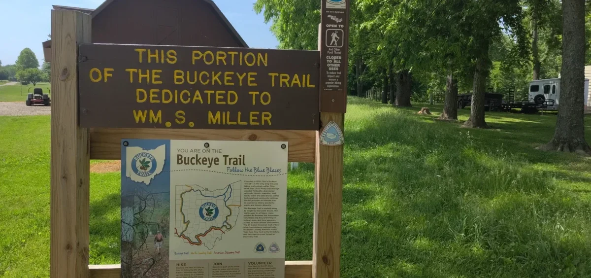 A wood sign with yellow lettering reads "This portion of the Buckeye Trail dedicated to W.M. S. Miller"