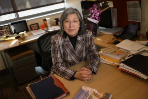 Louisa Ha poses for a picture while sitting at her desk.