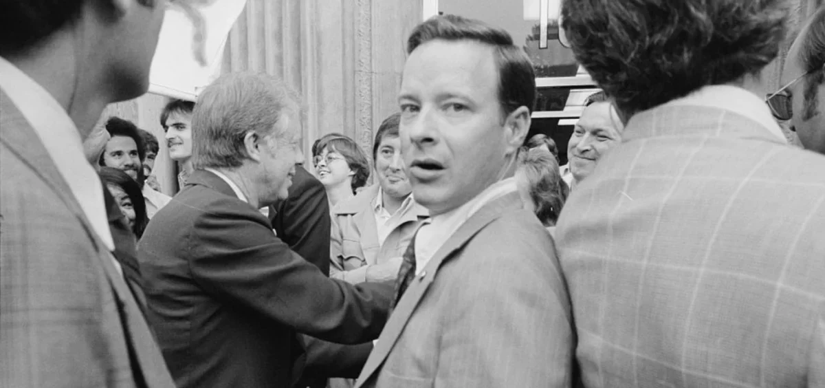 Jimmy Carter shaking hands with people in a crowd in this black and white photo.