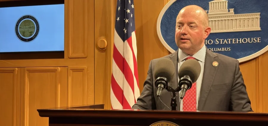 Rep. Brian Stewart stands behind a podium at a press conference.