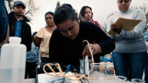A woman tests the water while people watch her.
