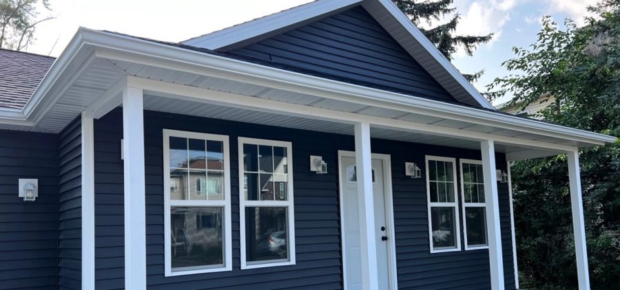 A blue home with white trim with a small concrete porch.