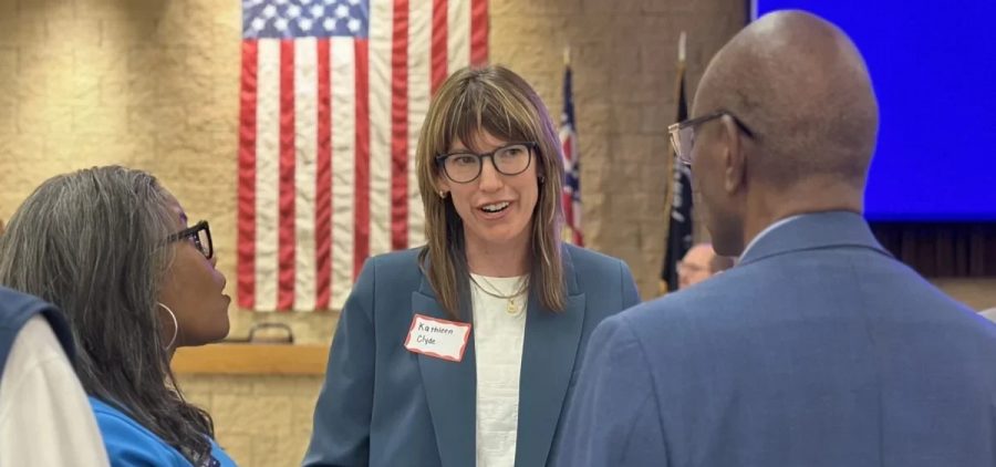 Kathleen Clyde is photographed talking to two people.