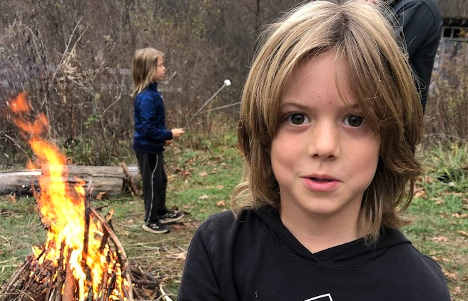 An image of three people outside by a campfire.