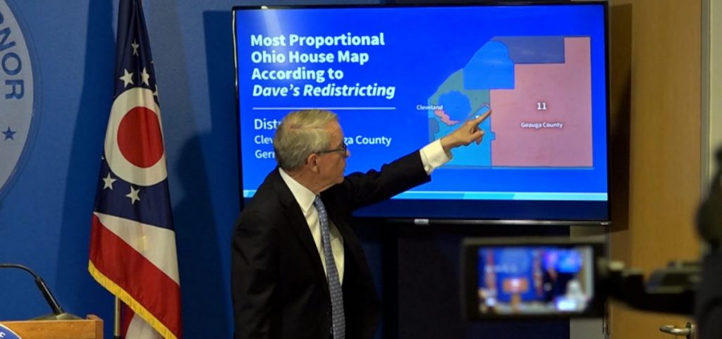 Gov. Mike DeWine points to a voting district map during a press conference.