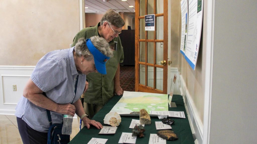 People on a private tour look at rocks and information on a table in the entranceway of the former Moundbuilders Country Club clubhouse