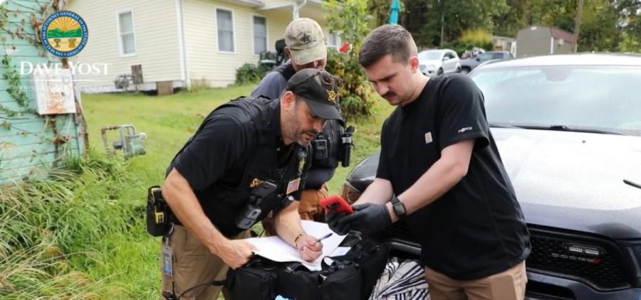 A screenshot of a video about Operation Next Door where three law enforcement officers look at a phone.