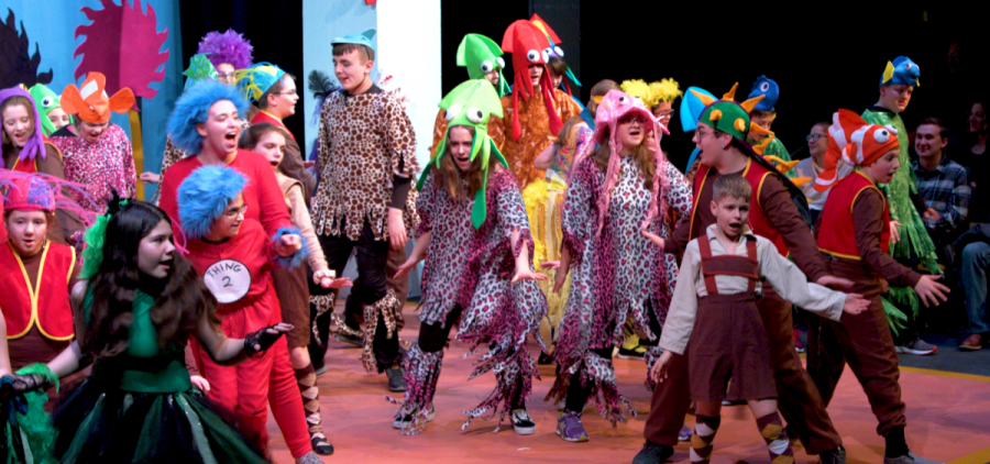 Many kids on stage in costume preforming.