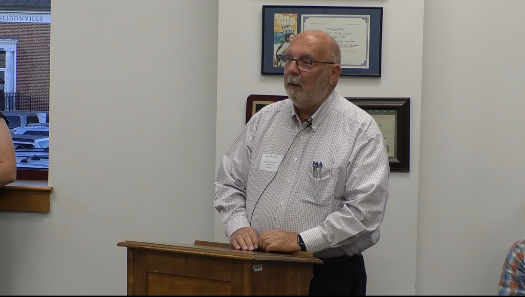 Fred Holmes stands at a podium at a roundtable event