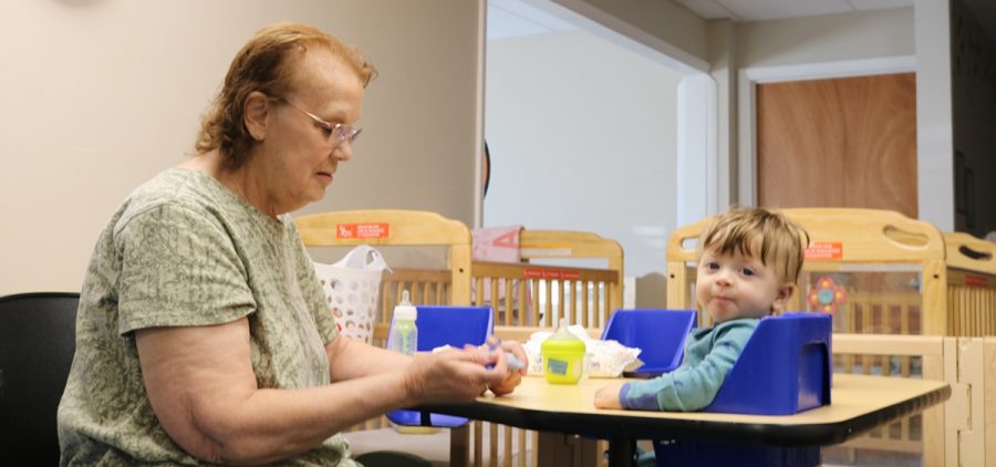A child care provider spoons baby food to an infant.