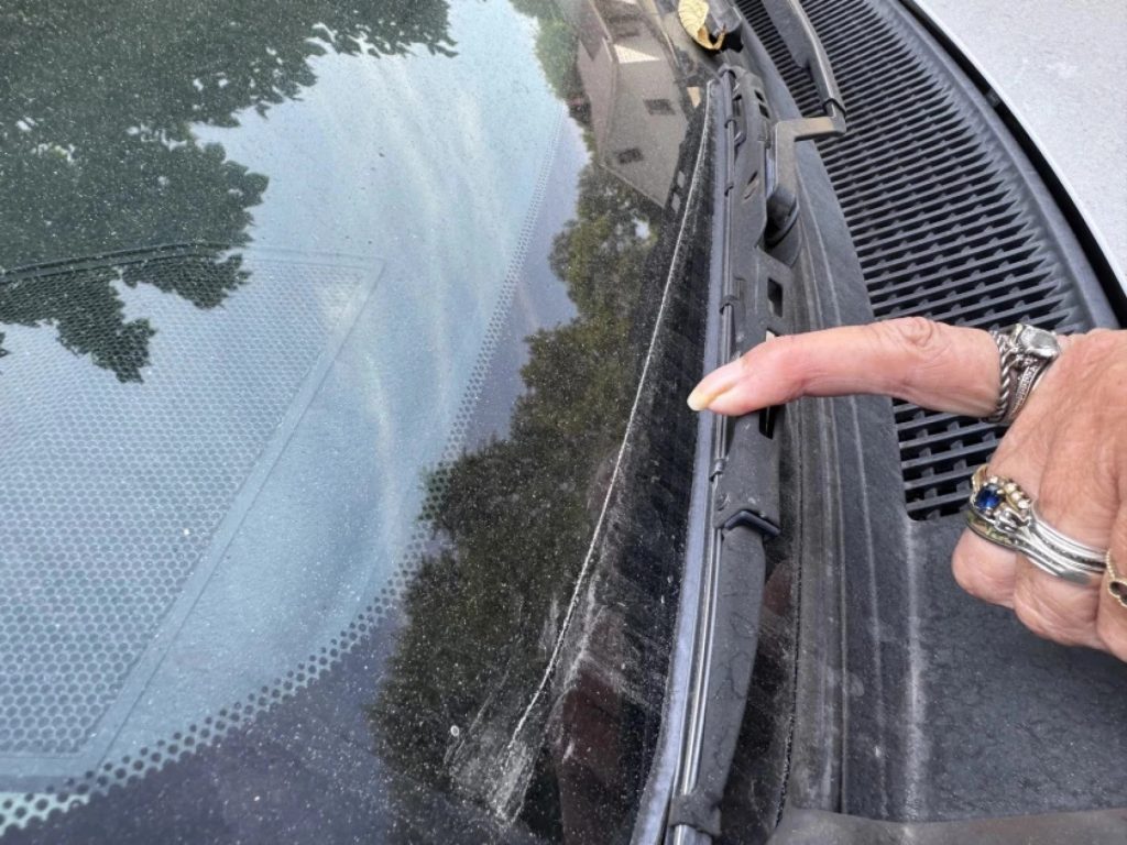 Donna Ballinger demonstrates how much fallout accumulates on her car overnight