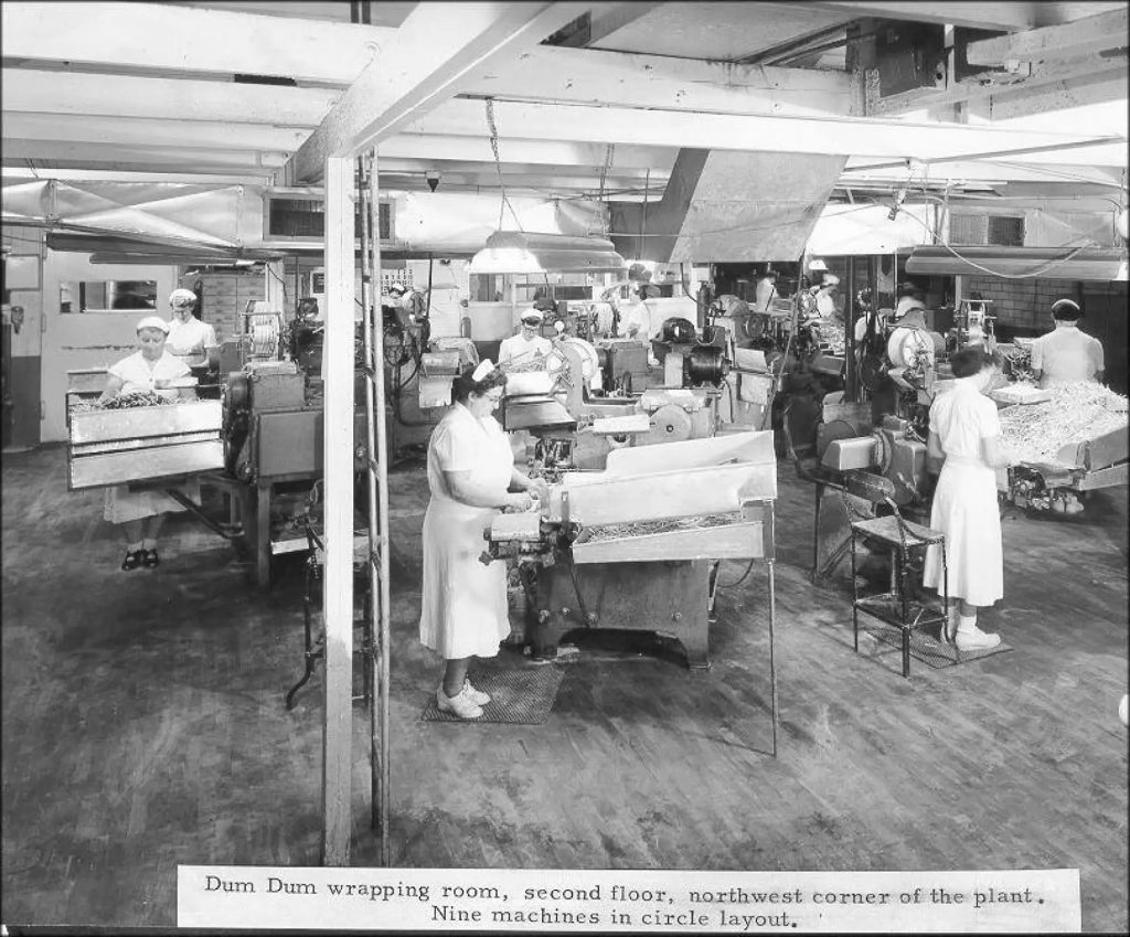 A black and white photo shows workers in the Spangler Candy Factory.