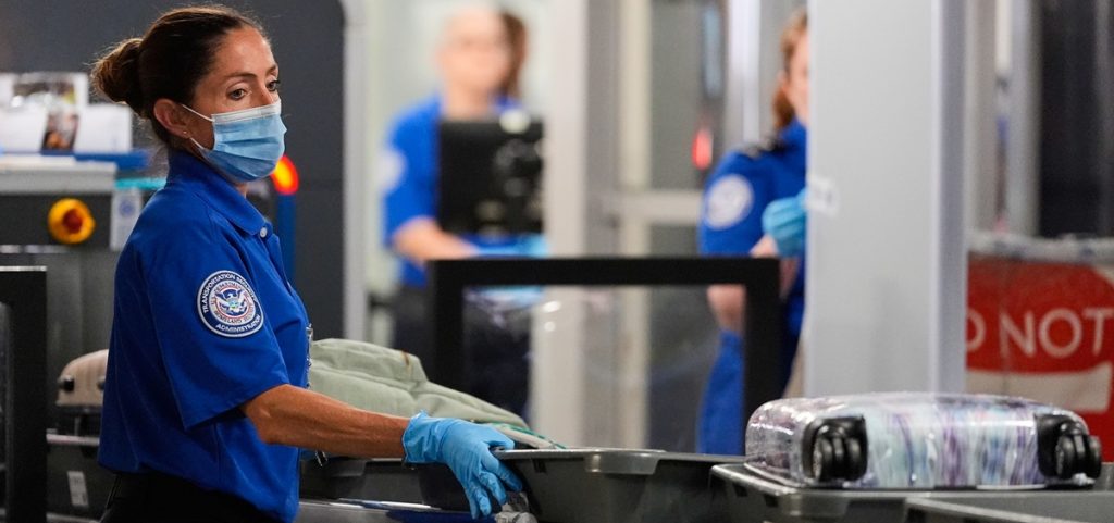 A TSA agent pushes bins along at a security checkpoint at the Dallas Fort Worth International Airport