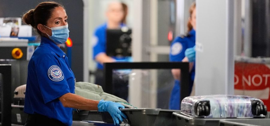 A TSA agent pushes bins along at a security checkpoint at the Dallas Fort Worth International Airport