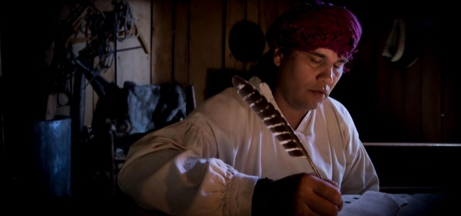James Greg Bilby as Sequoyah wearing native attire and holding a quill to write.