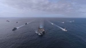 Multiple battle ships pictured on the ocean.