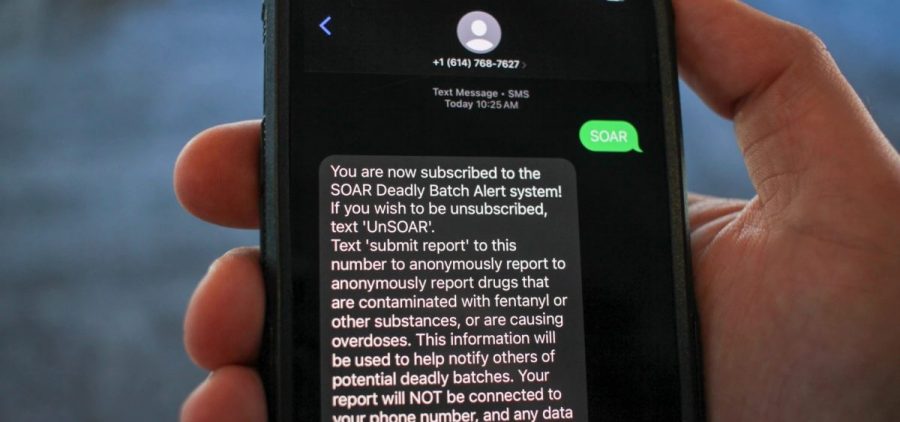 Someone holds a cellphone with a text message from the SOAR Initiative