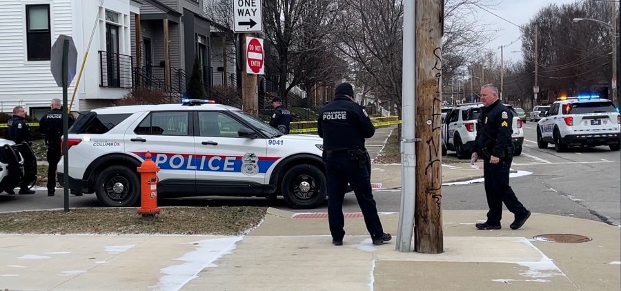 Two Columbus Police officers stand in front of a cruiser parked on the street at the scene of a double homicide on the 1400 block of N. 4th Street.