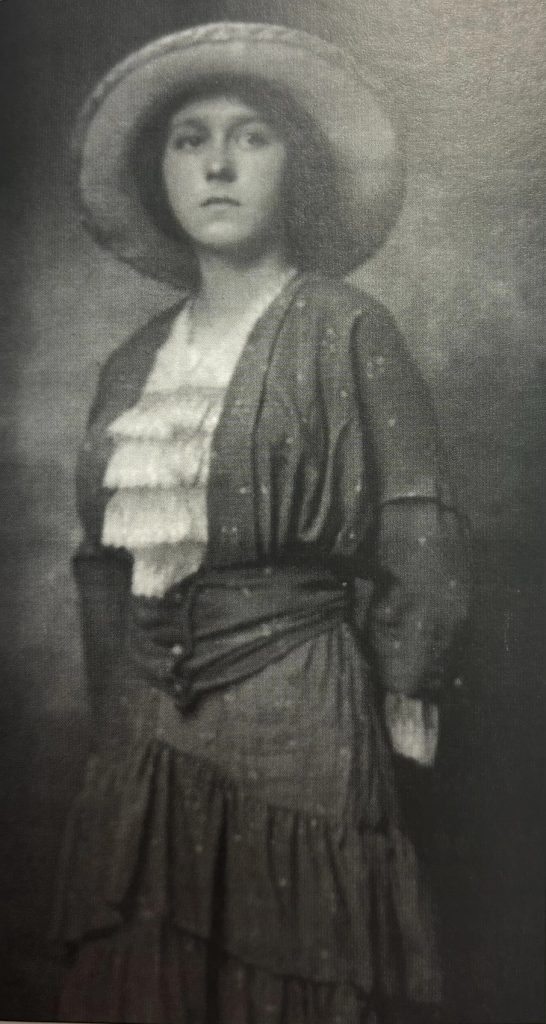 A black and white portrait of Maude Collins standing up