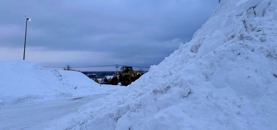 A snowplow works among piles of snow in Lowville, N.Y.