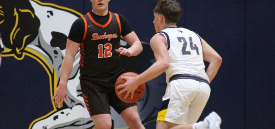 South Point player in white jersey dribbling the ball against Nelsonville York player in black jersey.