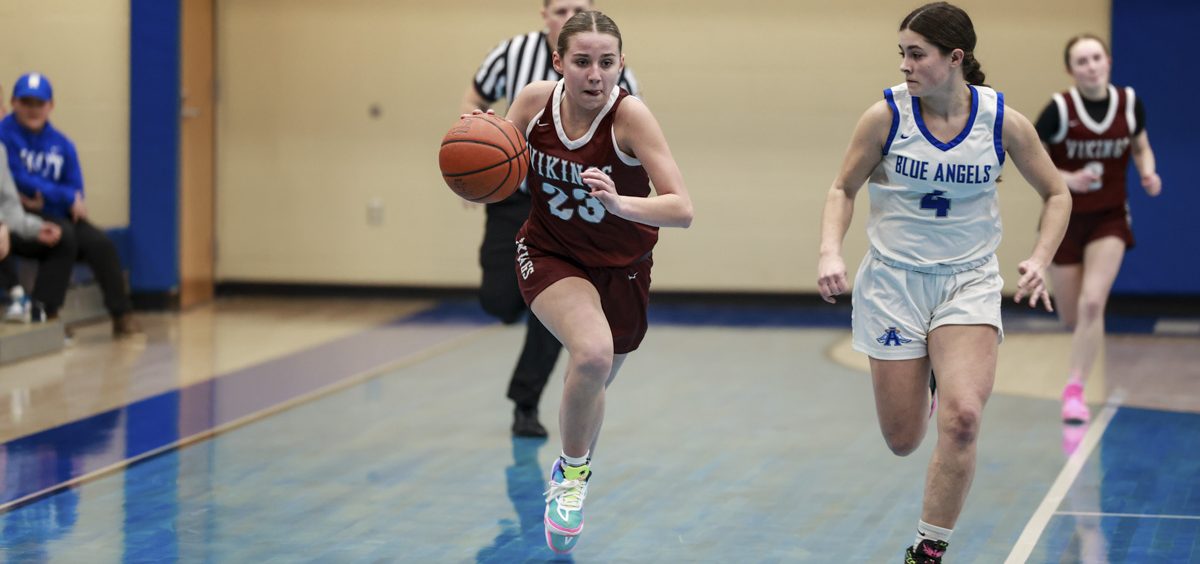 Alissa Perry runs the ball up the court, trying to get past her Blue Angel defender.