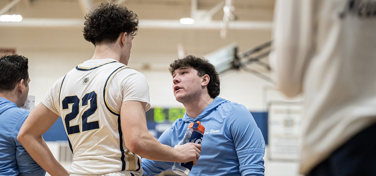 The Notre Dame Titan player gets a pep talk from a coach after subbing out from the game.