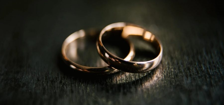 Two wedding rings are on top of each other on a table