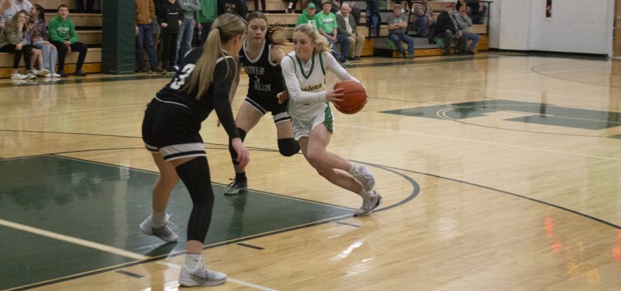 Lady Eagle drives towards the basketball with two River Valley defenders guarding her.