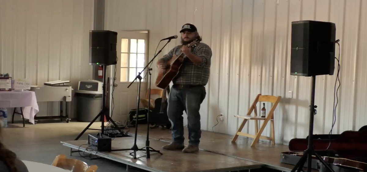A local musician plays guitar and sings for the Shine for the Mine fundraiser.