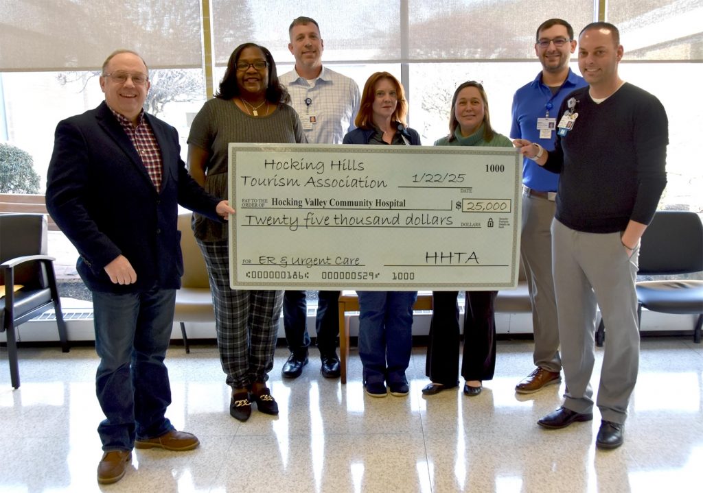 A group of people hold a ceremonial large check.
