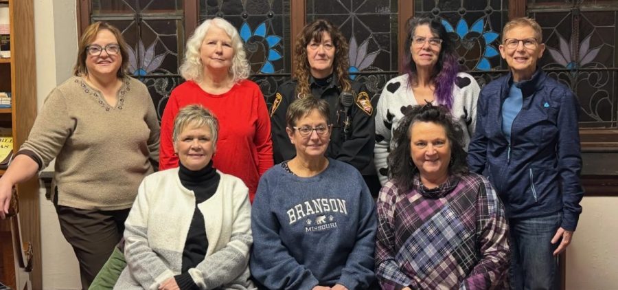 Eight women pose together smiling.