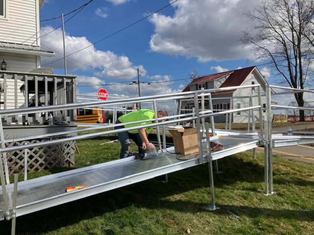 A person in a neon yellow shirt helps install a accessible ramp.