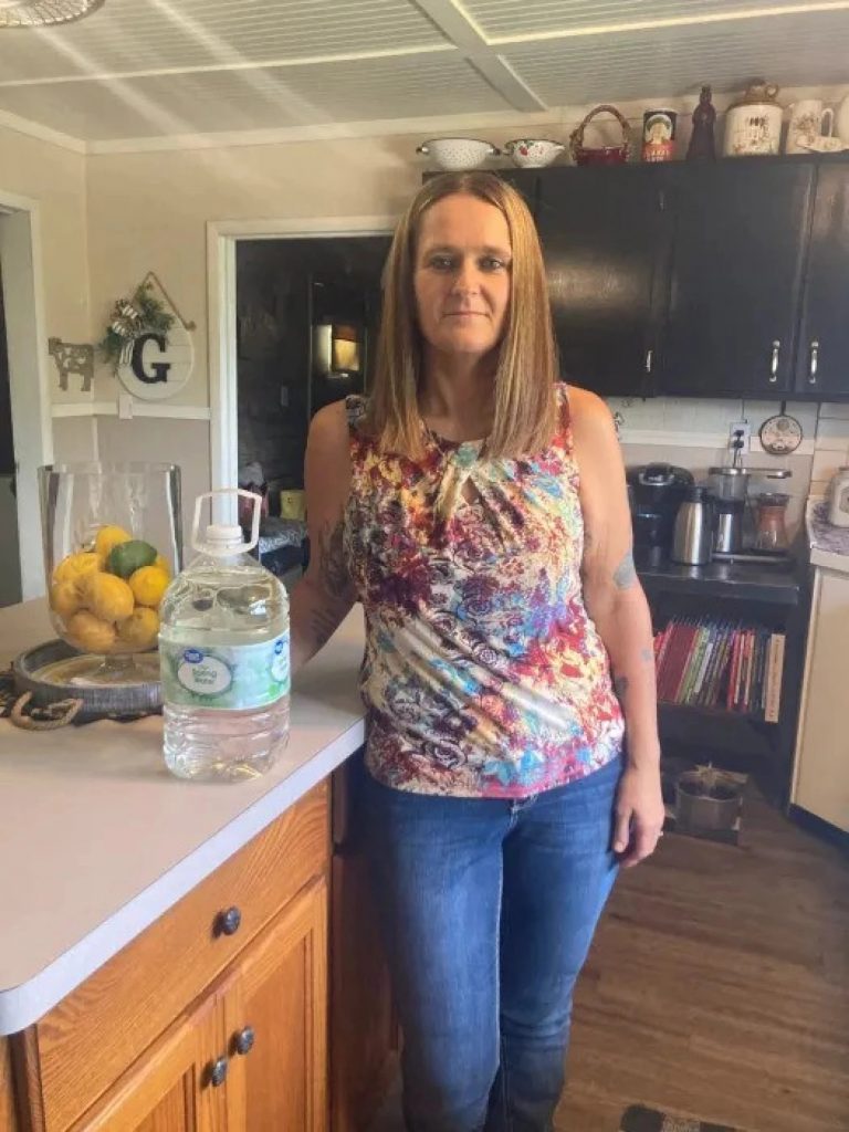 Tonya Shockey stands in her kitchen with a jug of water on the counter.