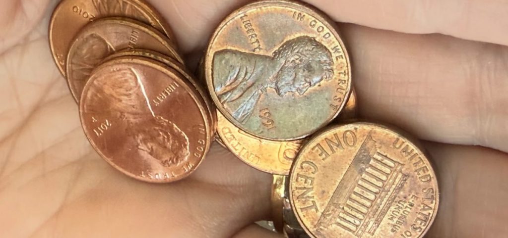 A hand holding pennies