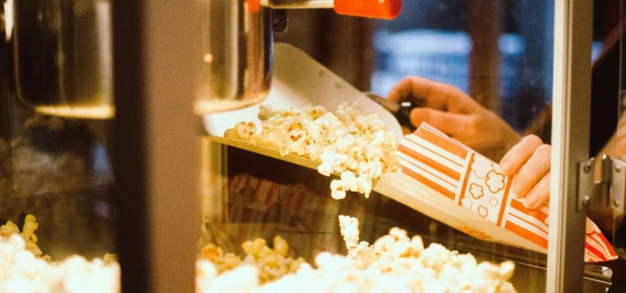 A person puts popcorn into a bag from a machine.