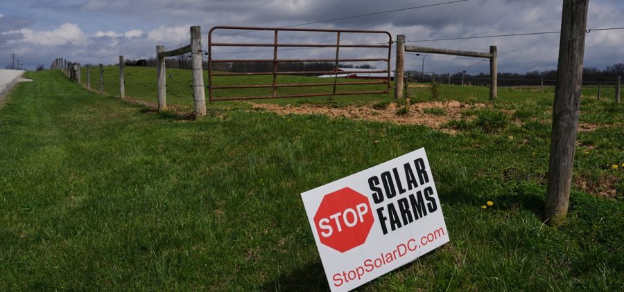 A sign opposing a nearby solar development sits near a pasture