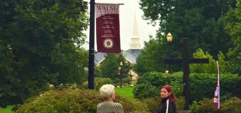 Two people stand under a street light on the campus of Walsh University