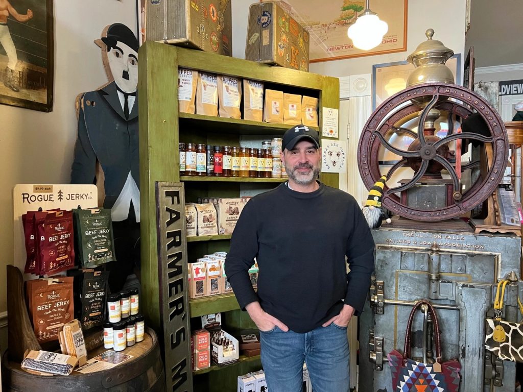 A man stands in front of displays in a tourist shop.