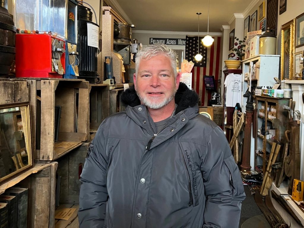 A man poses for a portrait smiling in a tourist store.