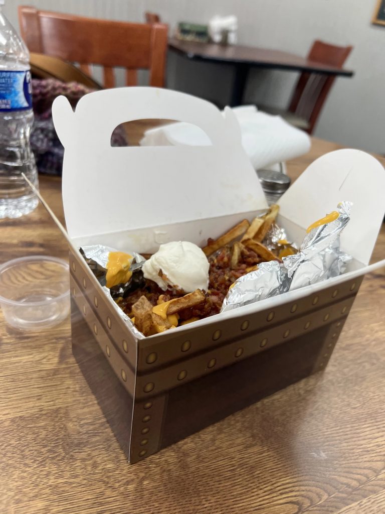 A paper box designed like a treasure chest has french fries in it.