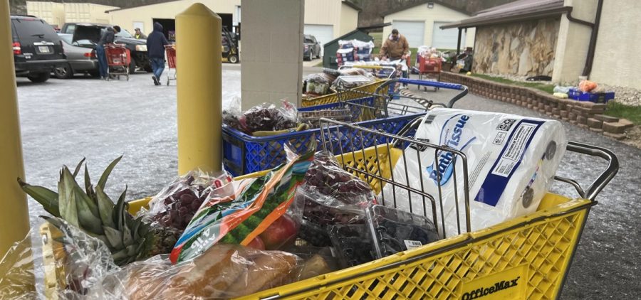 Shopping carts are filled with groceries while people go through them.