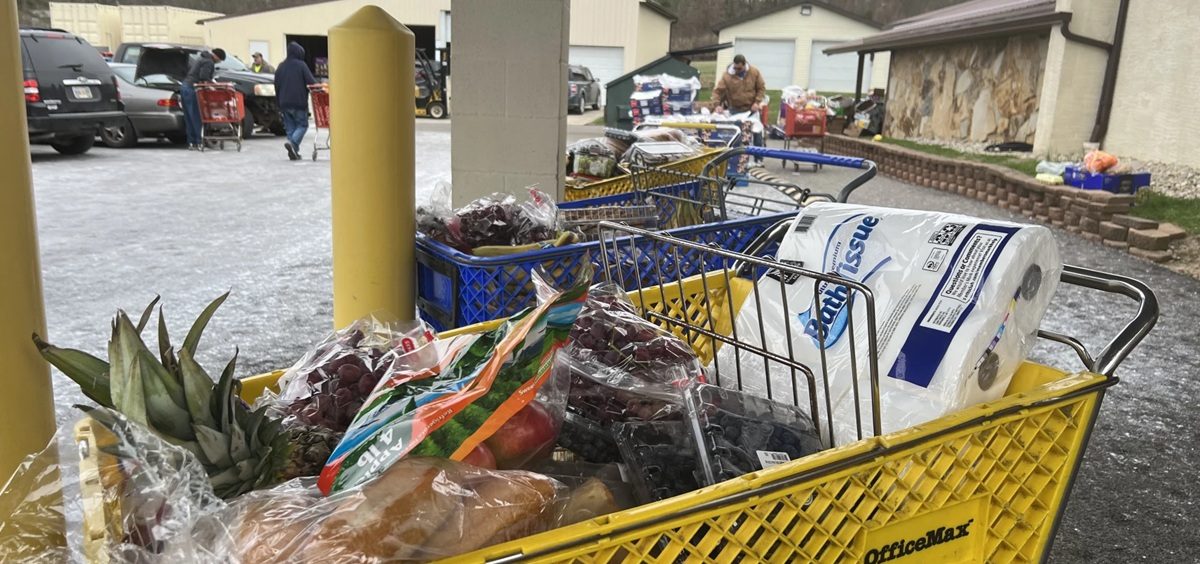 Shopping carts are filled with groceries while people go through them.