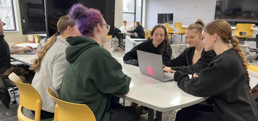 Students at Tiffin University discuss a cold case at a table.